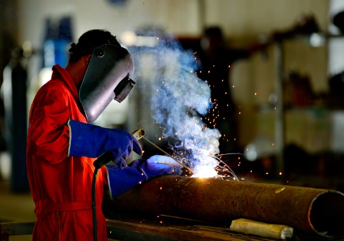 A fabricator welding a pipe together during Custom Metal Fabrication