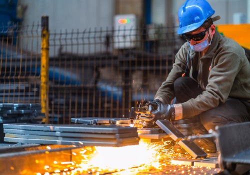 Un hombre cortando piezas de metal como parte de la fabricación de metal para Columbia SC