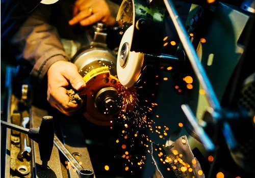 A worker is seen grinding metal. SMF offers steel fabrication.
