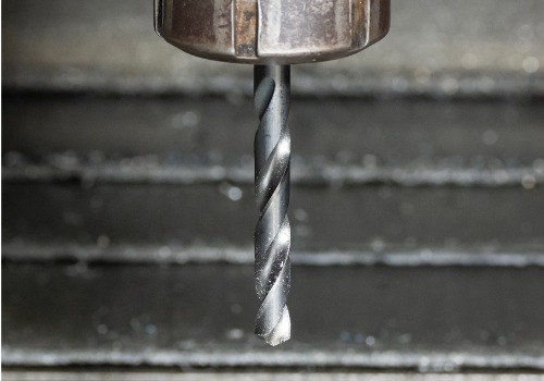 A drill bit is seen preparing to drill into metal. SMF offers steel fabrication in Greenville SC.