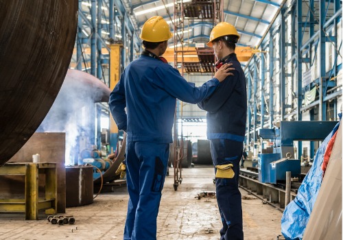 Dos trabajadores hablan en la fábrica. SMF ofrece fabricación de acero en Columbia SC.