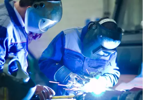 Se ve a dos soldadores trabajando juntos. ¿Por qué es importante la fabricación de metal? Llama a SMF.