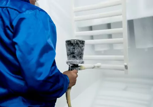 ¿Para qué sirve el recubrimiento en polvo? Se ve a un operario trabajando en una cabina de pintura en polvo. SMF ofrece servicios de pintura en polvo.